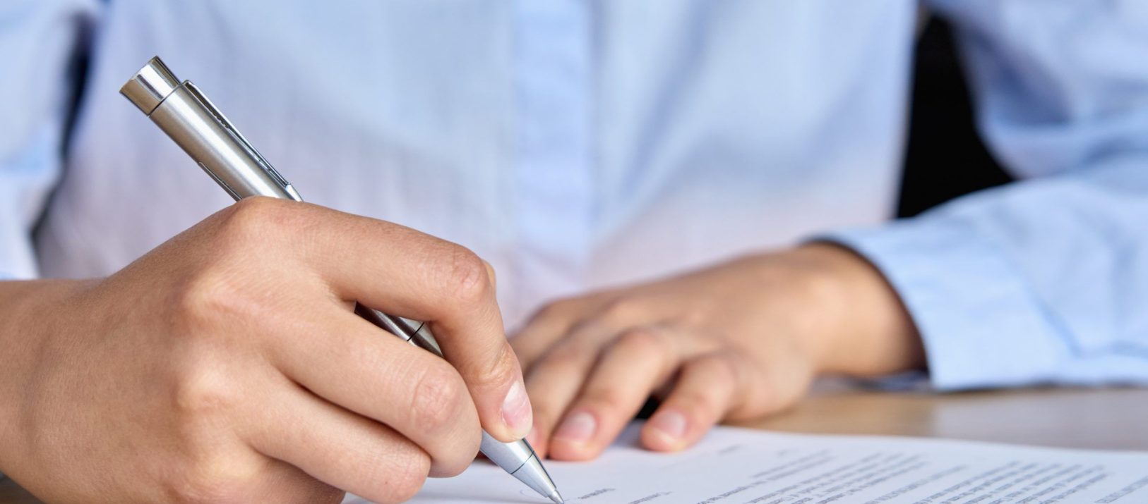 Closeup view of female corporation ceo business woman client hand signing putting signature on credit bank legal document, job contract, insurance agreement writing with pen on desk in office.