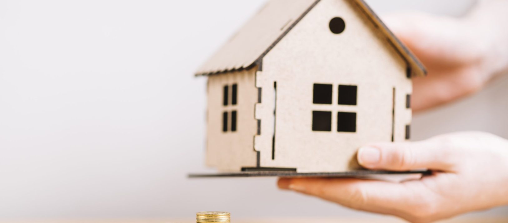 crop-hand-holding-house-near-coins